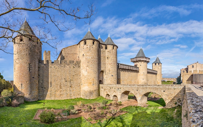 Château Comtal of Carcassonne with stone towers and arched bridge in France.