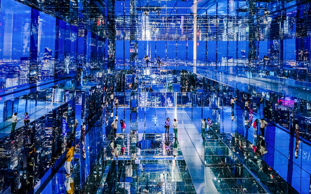 Guests exploring mirrored observation deck at Summit One Vanderbilt, New York City, at night.