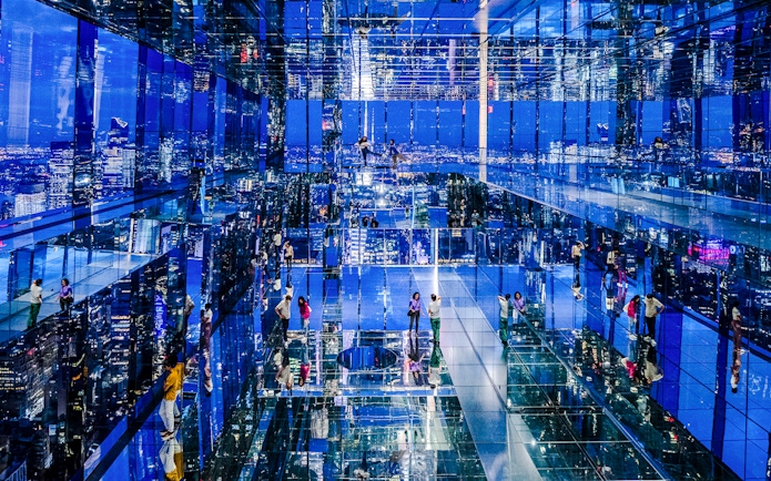 Guests exploring mirrored observation deck at Summit One Vanderbilt, New York City, at night.