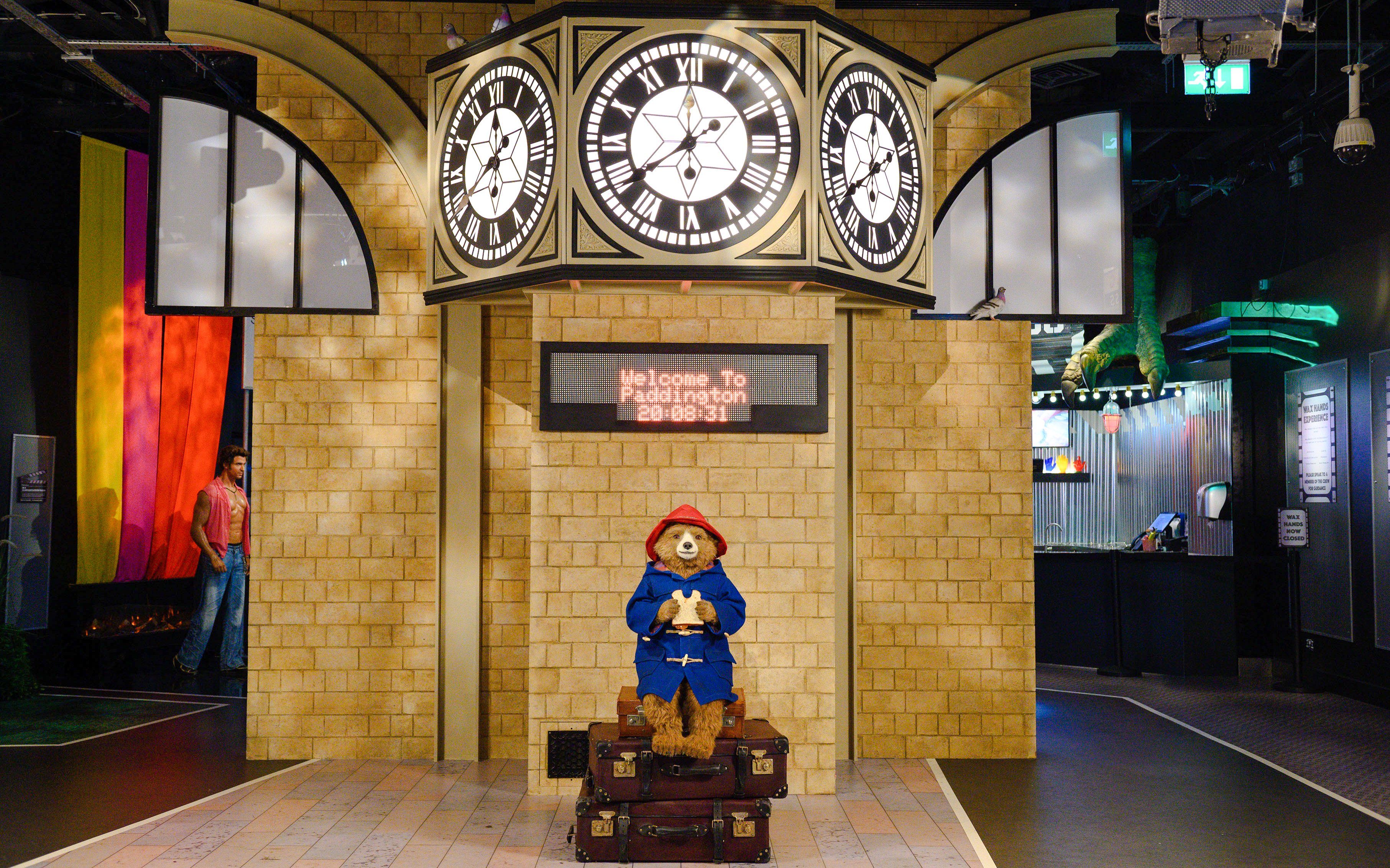 Paddington Bear statue at Madame Tussauds London under a clock display.
