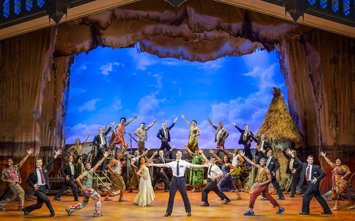 Stage performance of The Book of Mormon cast in Brisbane, featuring vibrant costumes and dynamic poses.