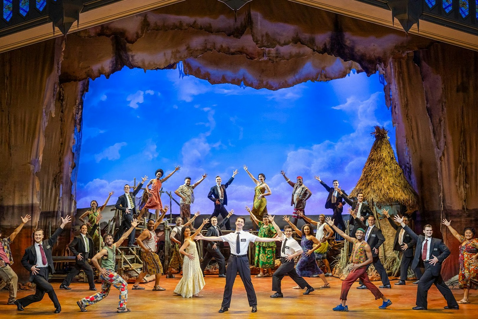 Stage performance of The Book of Mormon cast in Brisbane, featuring vibrant costumes and dynamic poses.