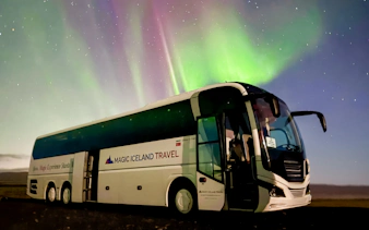 Coach under Northern Lights in Reykjavik, Iceland.