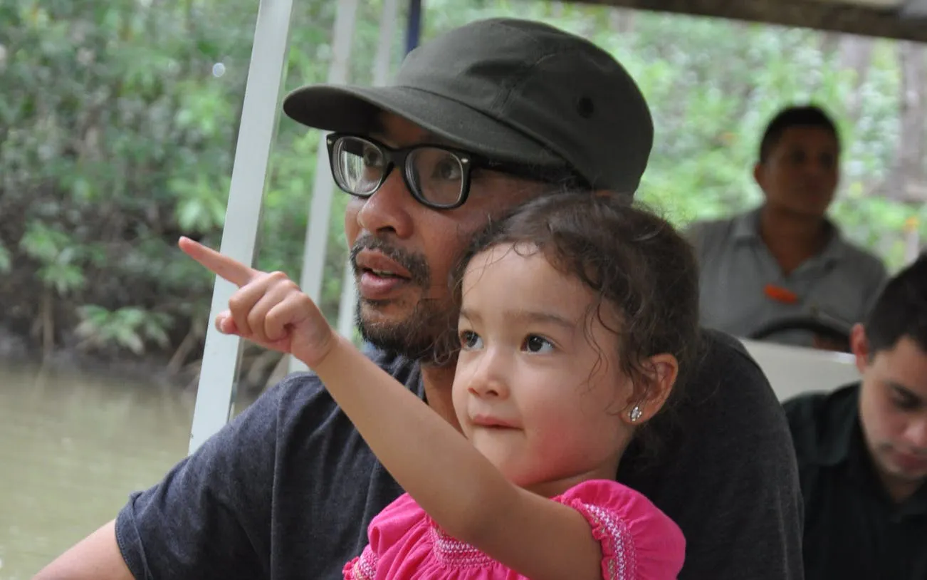 Father and daughter on Isla Damas mangrove boat tour, pointing at wildlife.