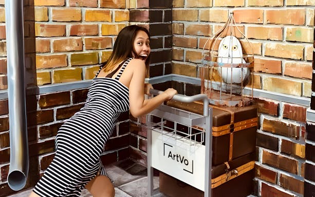 Person interacting with ArtVo Illusions exhibit, Gold Coast, featuring a trolley and owl in a cage.