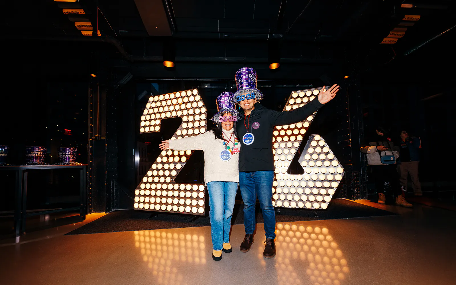 Visitors celebrating at One Times Square Skywalk with illuminated 2026 sign.