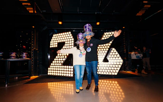 Visitors celebrating at One Times Square Skywalk with illuminated 2026 sign.