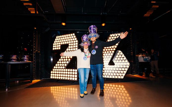 Visitors celebrating at One Times Square Skywalk with illuminated 2026 sign.