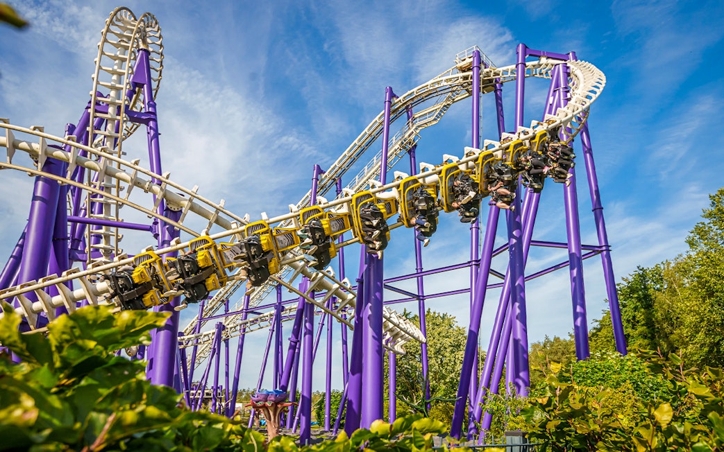 Roller coaster at Heide Park with riders on a loop against a blue sky.