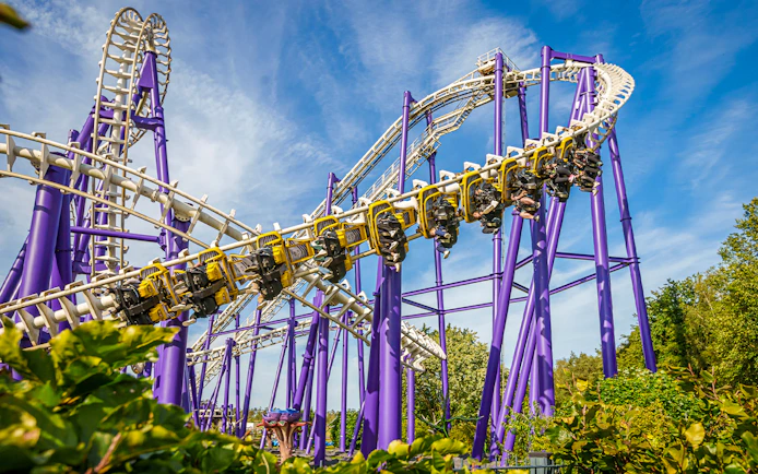 Roller coaster at Heide Park with riders on a loop against a blue sky.