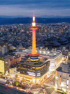 Kyoto Tower illuminated at night, overlooking the cityscape of Kyoto, Japan.