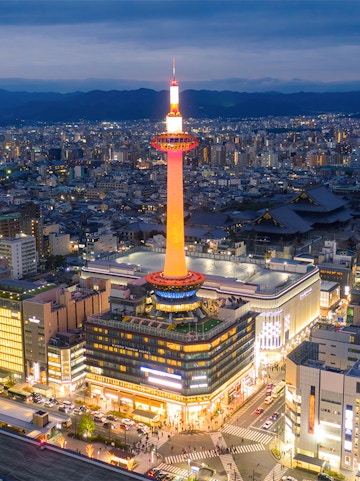 Kyoto Tower illuminated at night, overlooking the cityscape of Kyoto, Japan.