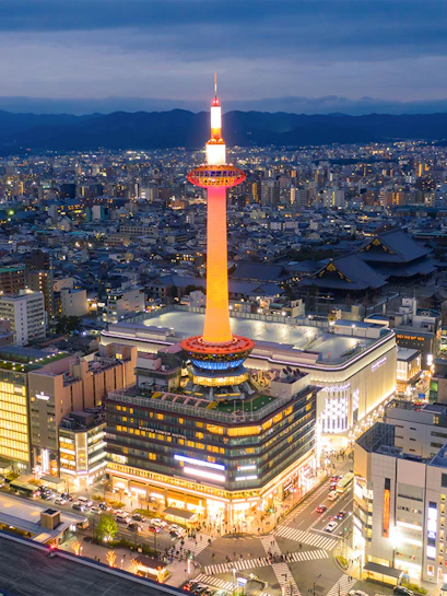 Kyoto Tower illuminated at night, overlooking the cityscape of Kyoto, Japan.