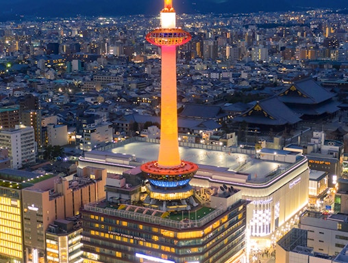 Kyoto Tower illuminated at night, overlooking the cityscape of Kyoto, Japan.