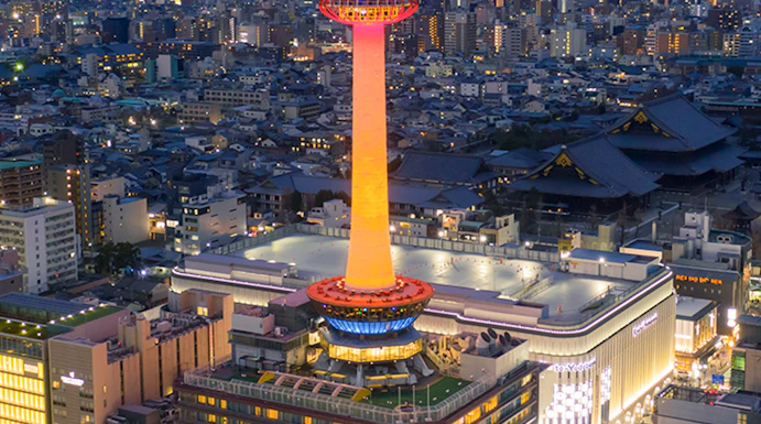 Kyoto Tower illuminated at night, overlooking the cityscape of Kyoto, Japan.