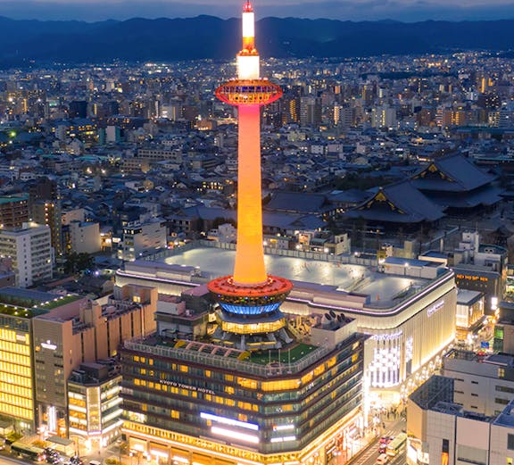 Kyoto Tower illuminated at night, overlooking the cityscape of Kyoto, Japan.