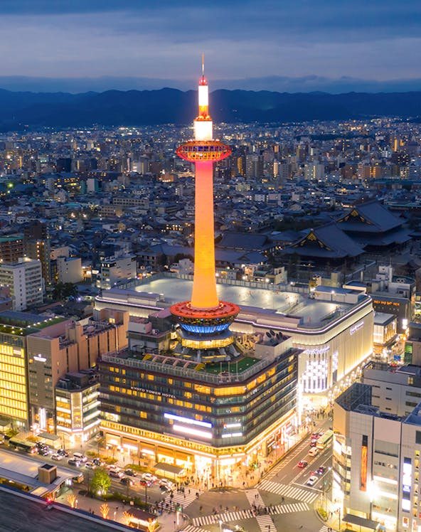 Kyoto Tower illuminated at night, overlooking the cityscape of Kyoto, Japan.