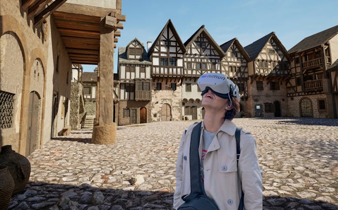 Person using VR headset in historic Prague square during guided tour.