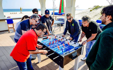 Tourists playing foosball at Al Majles Resort with beach view in the background.