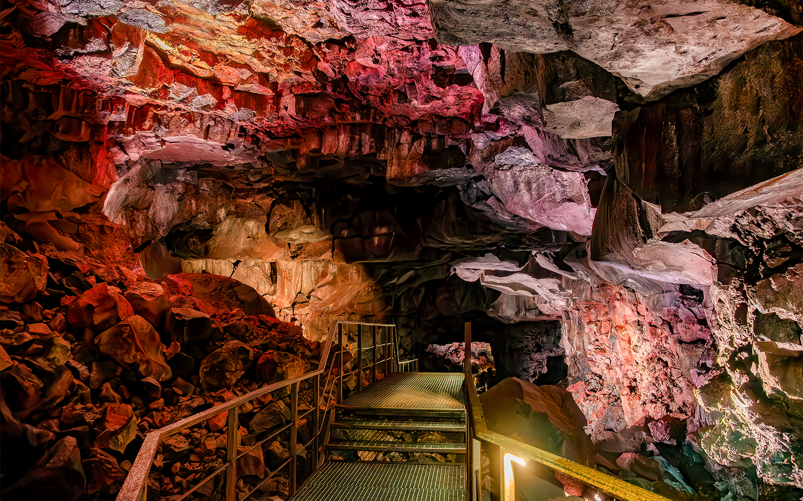 Walkway inside Raufarhólshellir Lava Cave, Iceland, with illuminated rock formations.