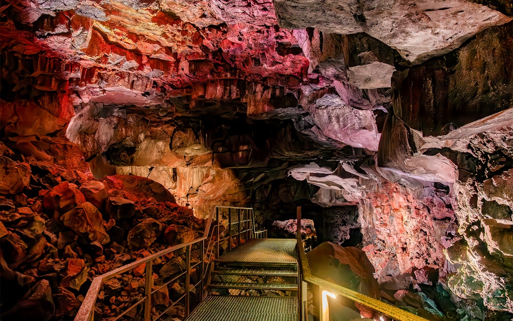 Walkway inside Raufarhólshellir Lava Cave, Iceland, with illuminated rock formations.