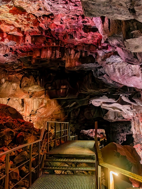 Walkway inside Raufarhólshellir Lava Cave, Iceland, with illuminated rock formations.