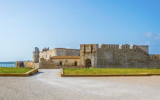 Maniace Castle entrance with stone walls and courtyard in Syracuse, Italy.