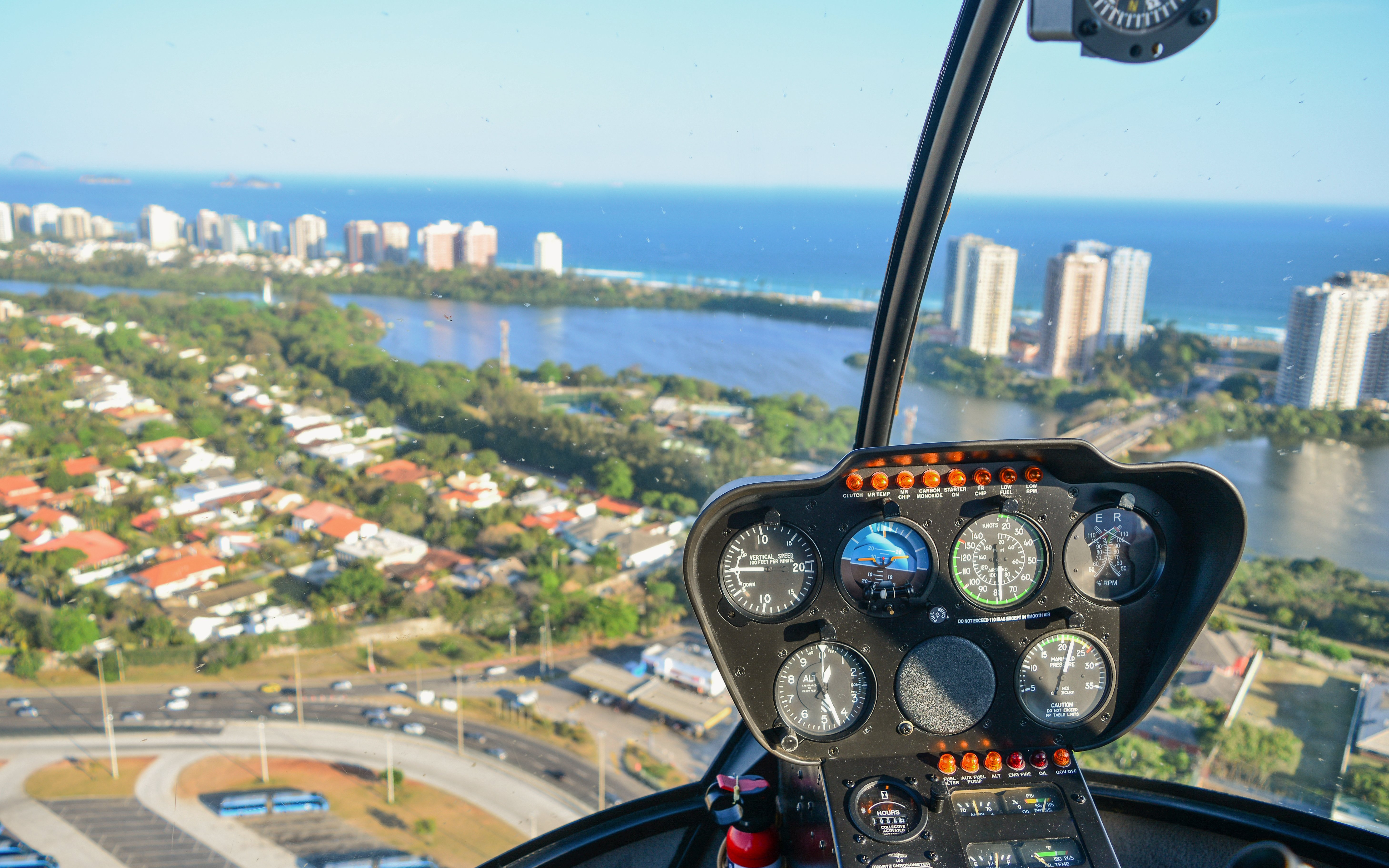Helicopter cockpit view over Rio de Janeiro with cityscape and ocean.