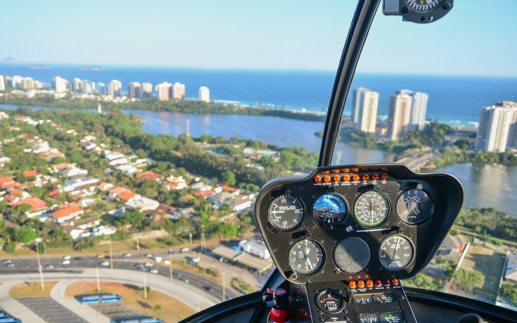 Helicopter cockpit view over Rio de Janeiro with cityscape and ocean.