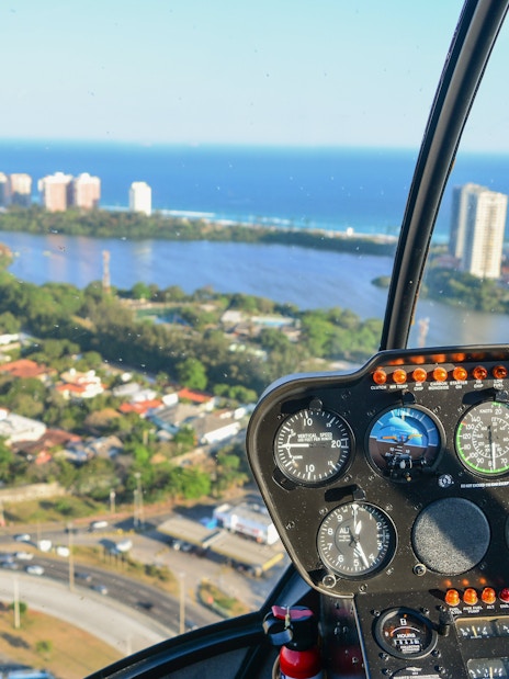 Helicopter cockpit view over Rio de Janeiro with cityscape and ocean.