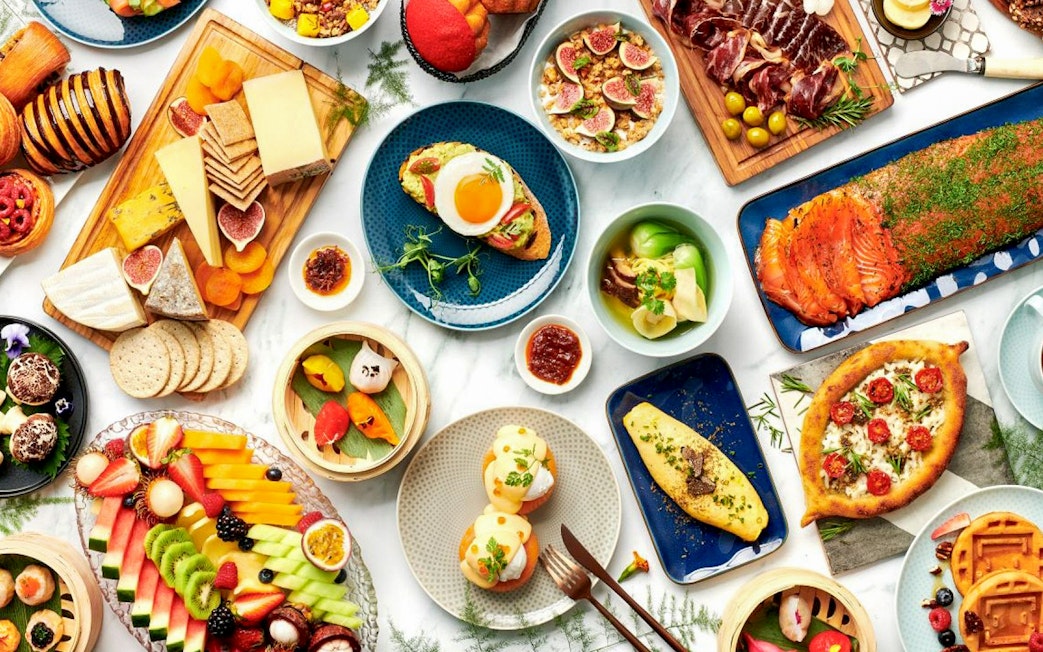 Assorted dishes at Gastronomy Buffet Dinner Experience, Dubai, featuring cheeses, fruits, and smoked salmon.