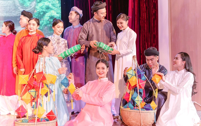 Performers in traditional Ao Dai costumes at a cultural show in Da Nang, holding colorful lanterns.