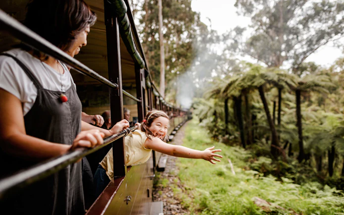 Young girl waves from Puffing Billy steam train window on Melbourne tour.