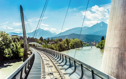 Bridge over the Inn River with mountain backdrop in Innsbruck, Austria.