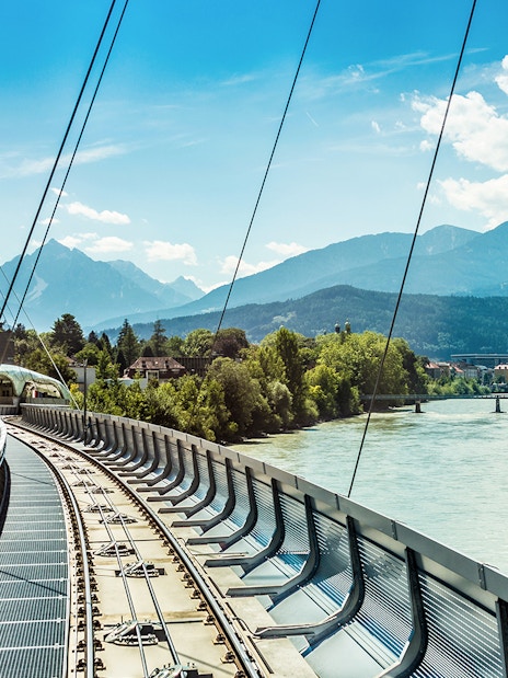 Bridge over the Inn River with mountain backdrop in Innsbruck, Austria.