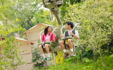 Tourists enjoying a canopy glider ride in a lush rainforest setting.
