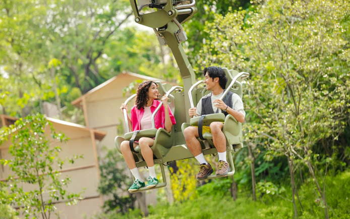 Tourists enjoying a canopy glider ride in a lush rainforest setting.