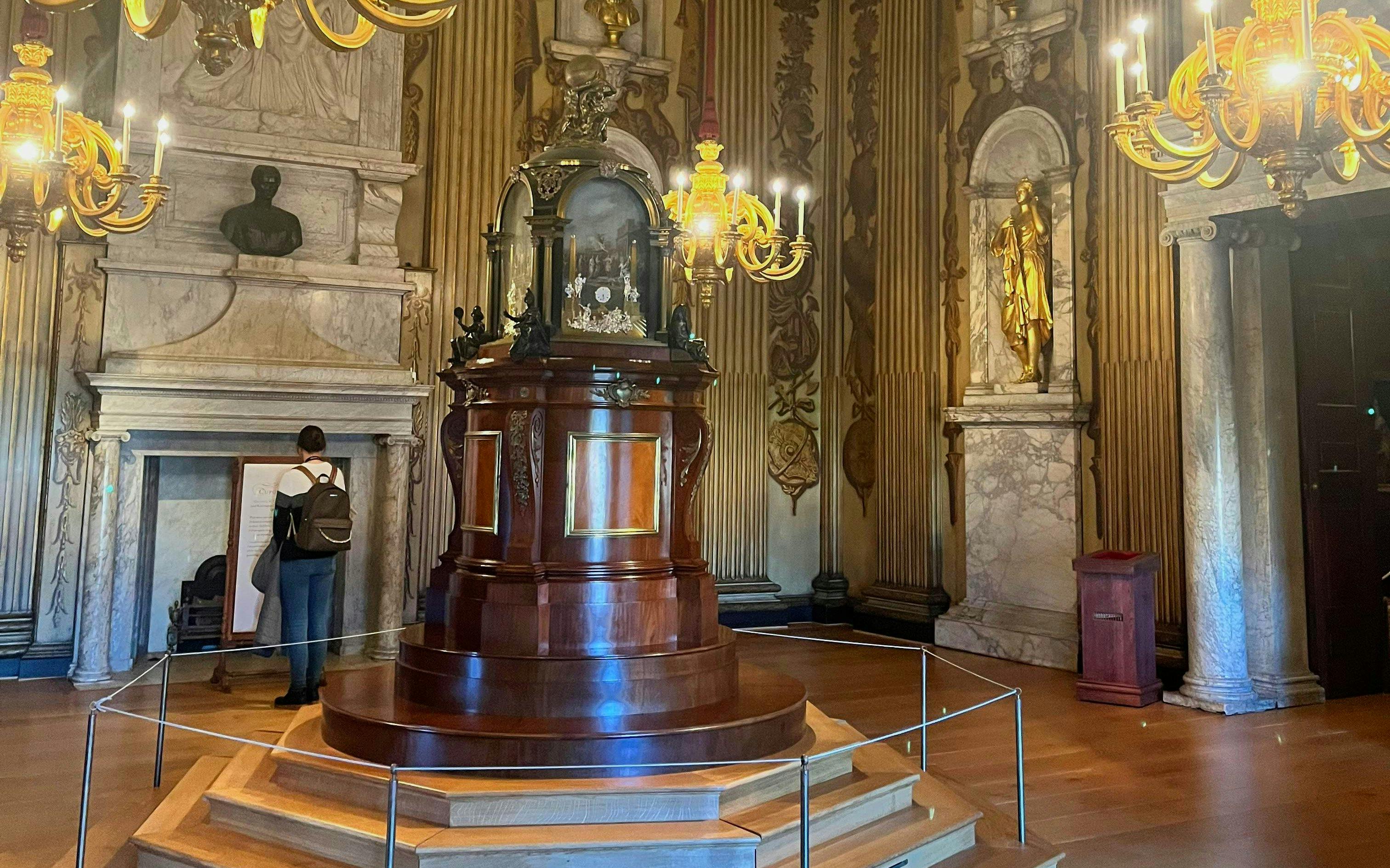 Cupola room with ornate chandeliers, marble fireplace, and central wooden structure.