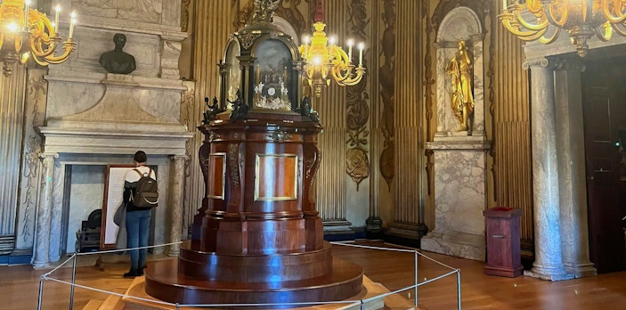 Cupola room with ornate chandeliers, marble fireplace, and central wooden structure.
