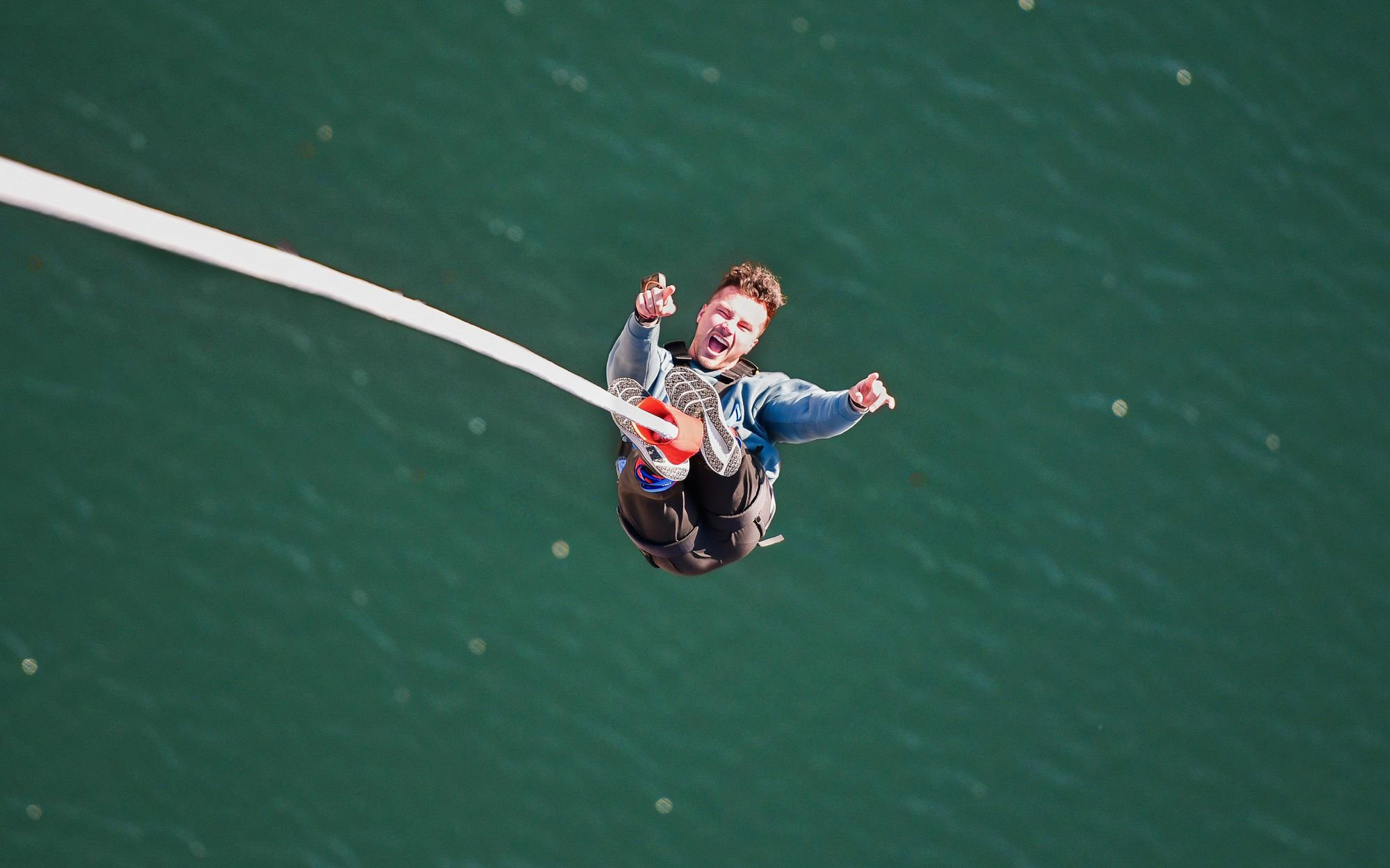 Person bungee jumping over water at Stockhorn, Interlaken.