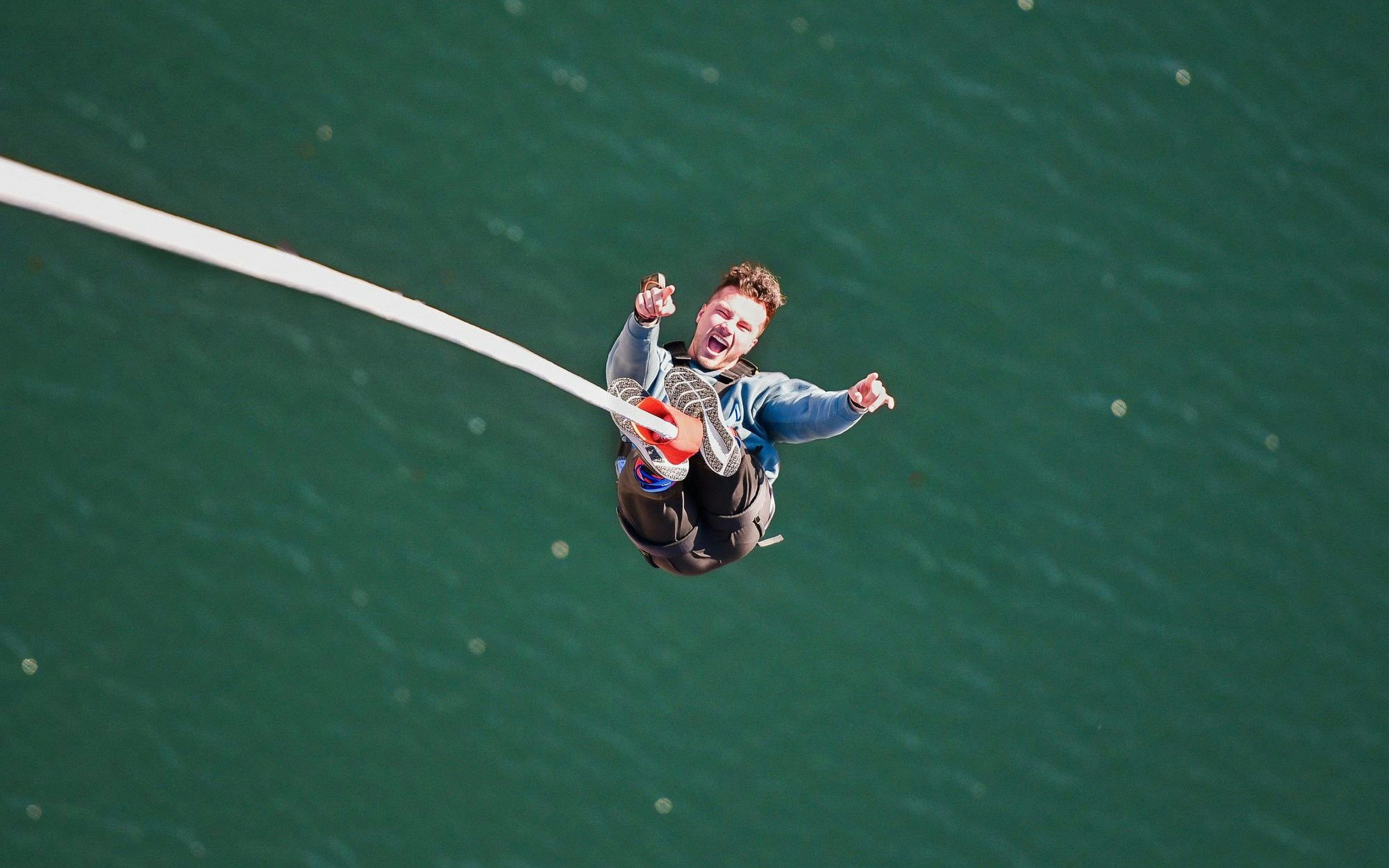 Person bungee jumping over water at Stockhorn, Interlaken.