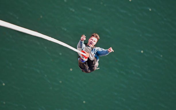 Person bungee jumping over water at Stockhorn, Interlaken.