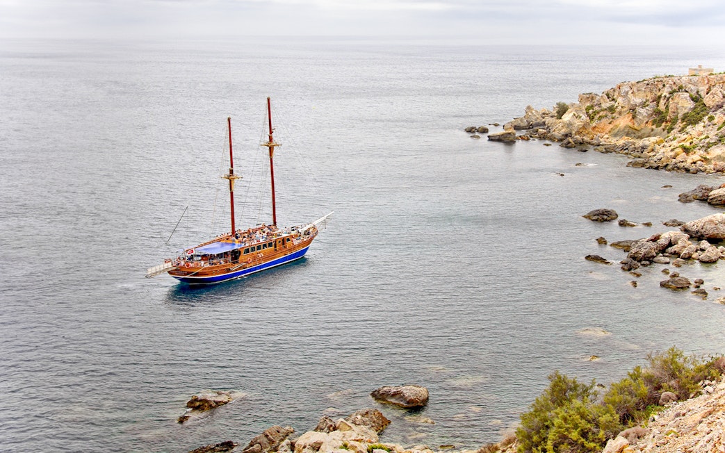Turkish gulet sailing near rocky coast from Sliema to Gozo and Comino.