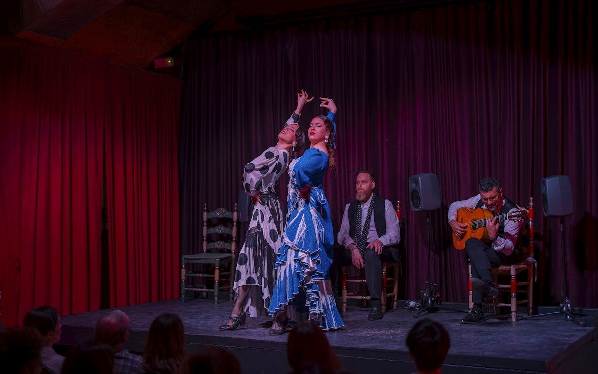 Flamenco dancers performing at Palau Dalmases with guitarist and audience in Barcelona.