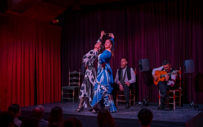 Flamenco dancers performing at Palau Dalmases with guitarist and audience in Barcelona.