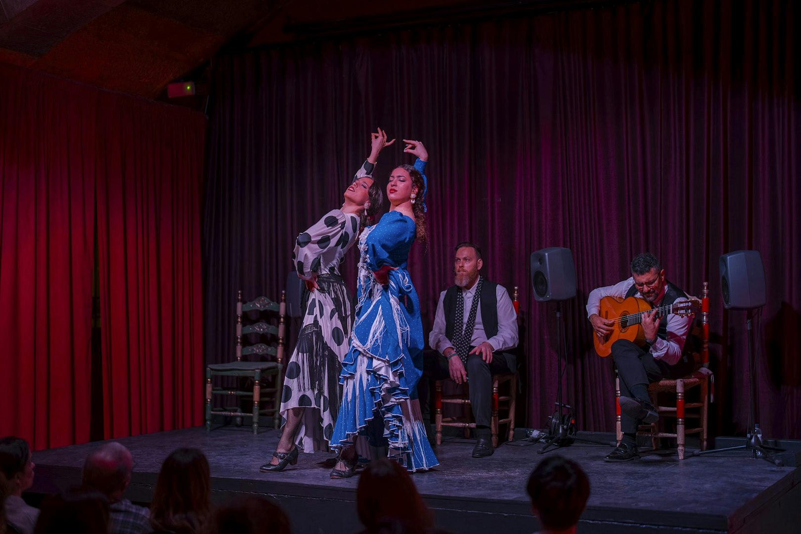 Flamenco dancers performing at Palau Dalmases with guitarist and audience in Barcelona.
