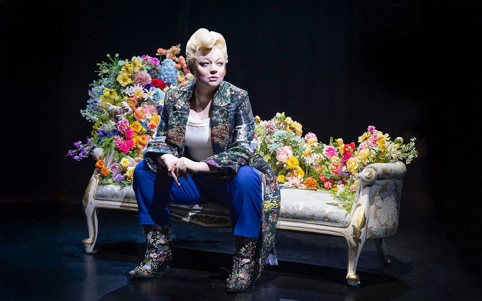Person seated on a floral-decorated couch, related to "The Picture of Dorian Gray" tour.