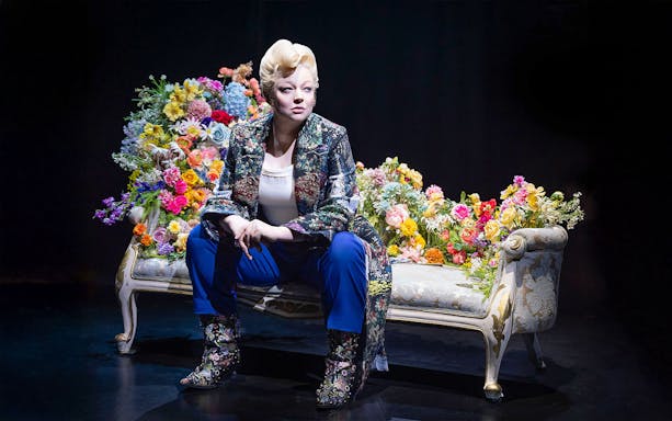 Person seated on a floral-decorated couch, related to "The Picture of Dorian Gray" tour.