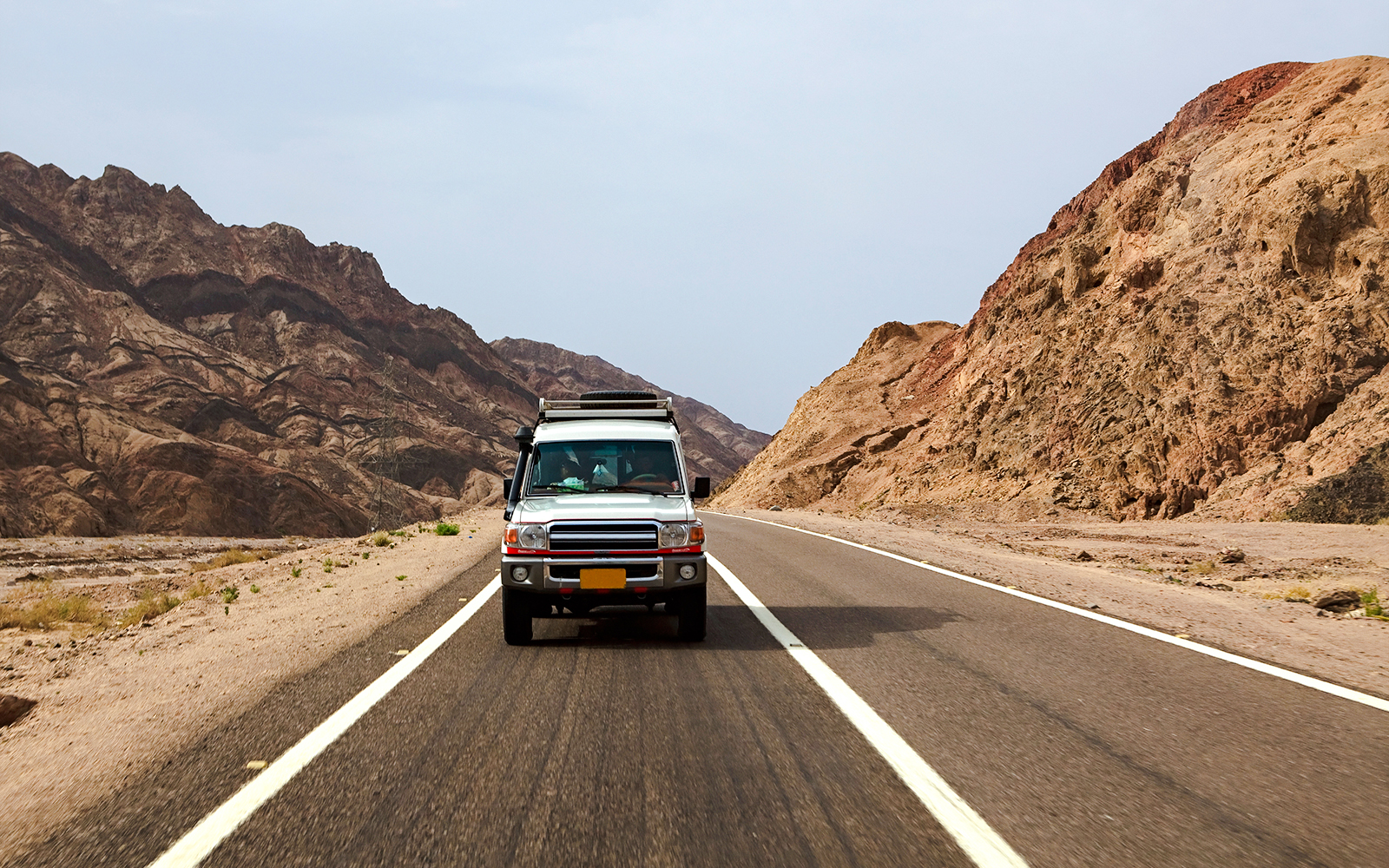 Car driving on a desert road through rocky landscape in Egypt.