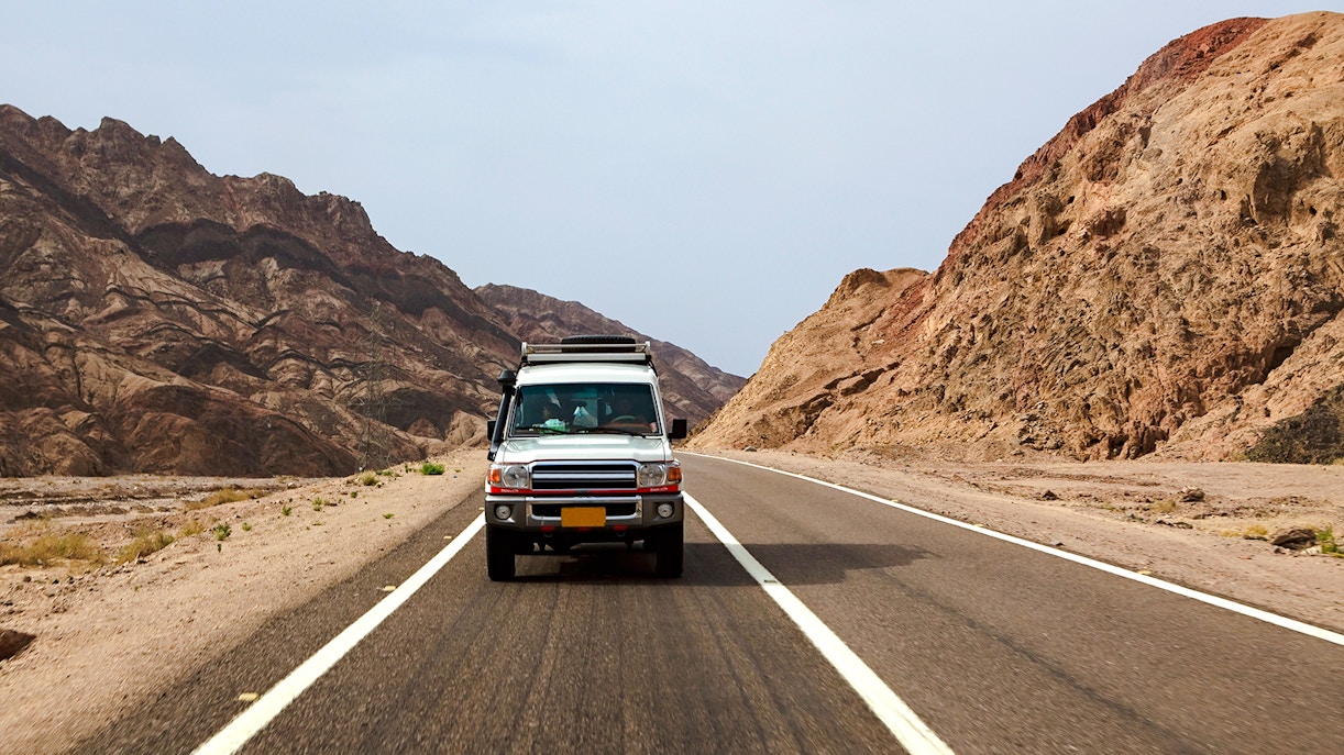 Car driving on a desert road through rocky landscape in Egypt.